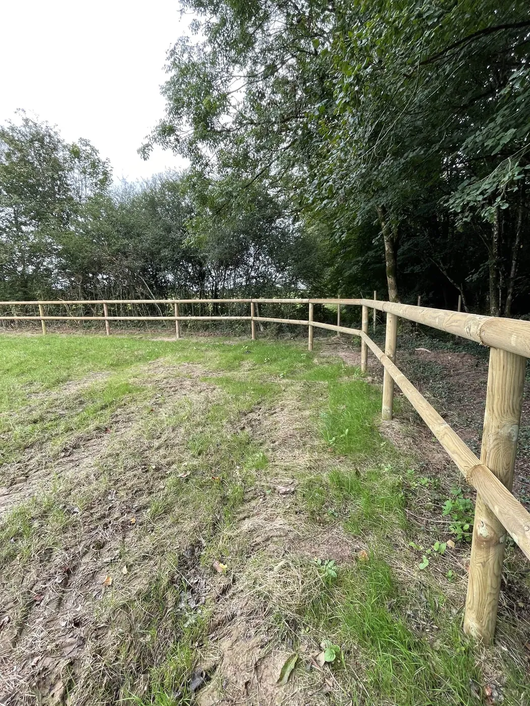 Clôture bois à lices installée dans un pré fraîchement travaillé